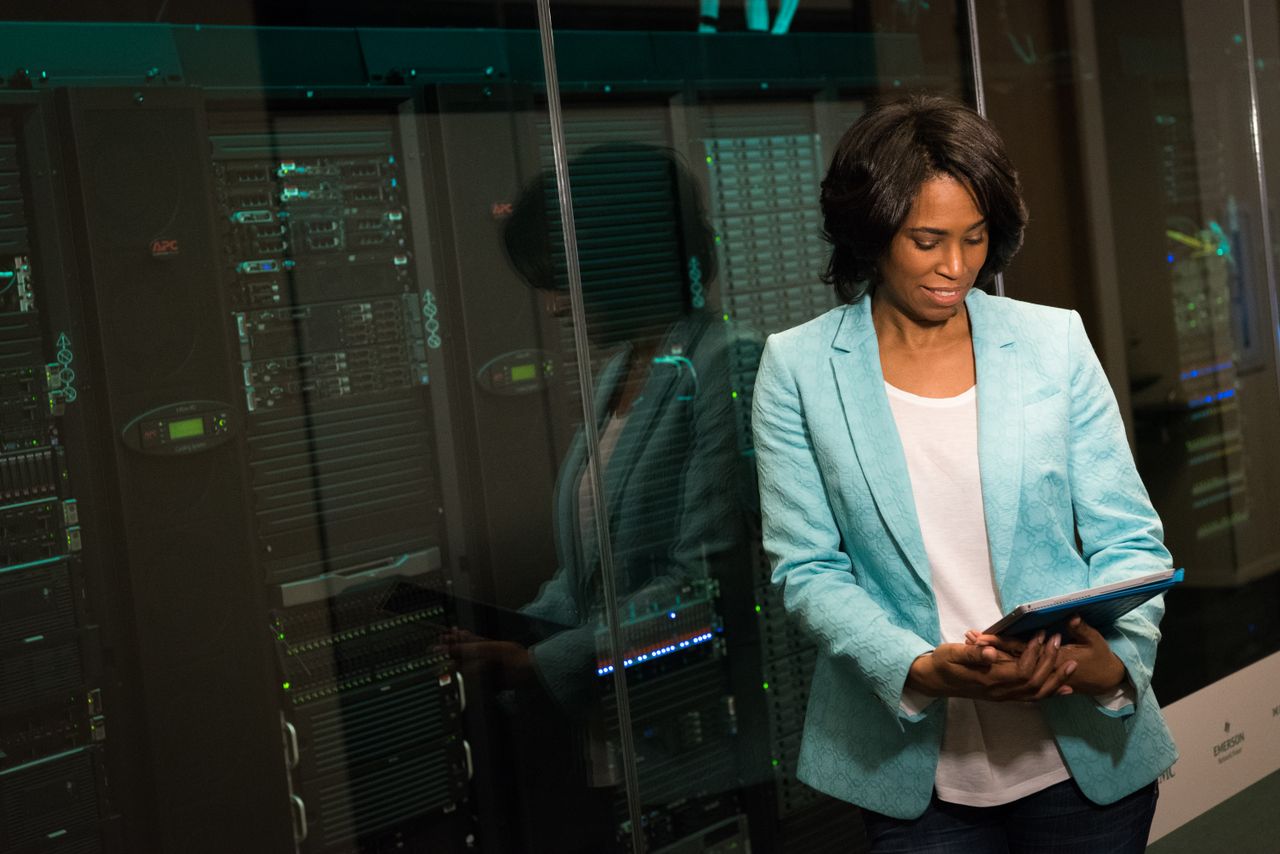 services-04 Female IT professional examining data servers in a modern data center setting.