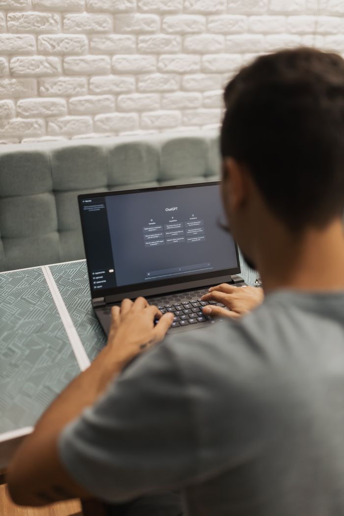 contact-img A man interacts with a laptop displaying the ChatGPT system indoors, focusing on technology.